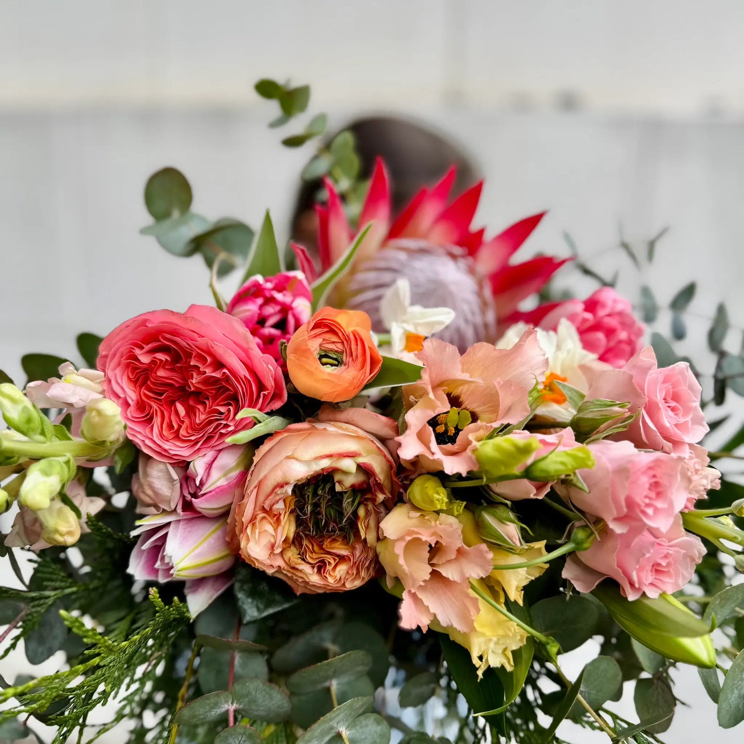 Bouquet of flowers with pink, orange, and green colors against a light background