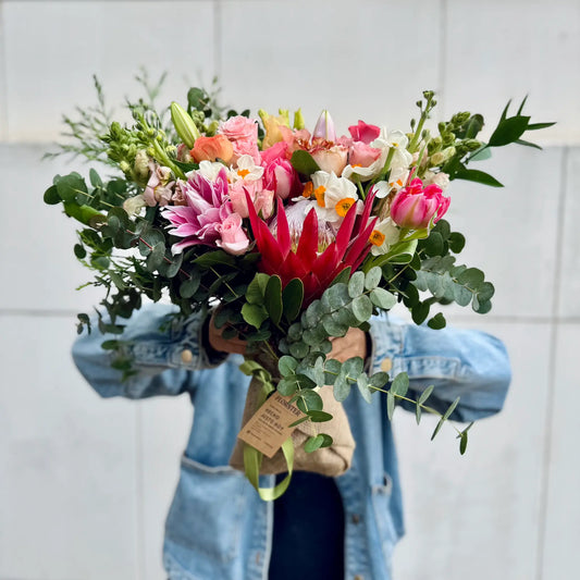 Bouquet of flowers held by a person wearing a denim jacket against a light background