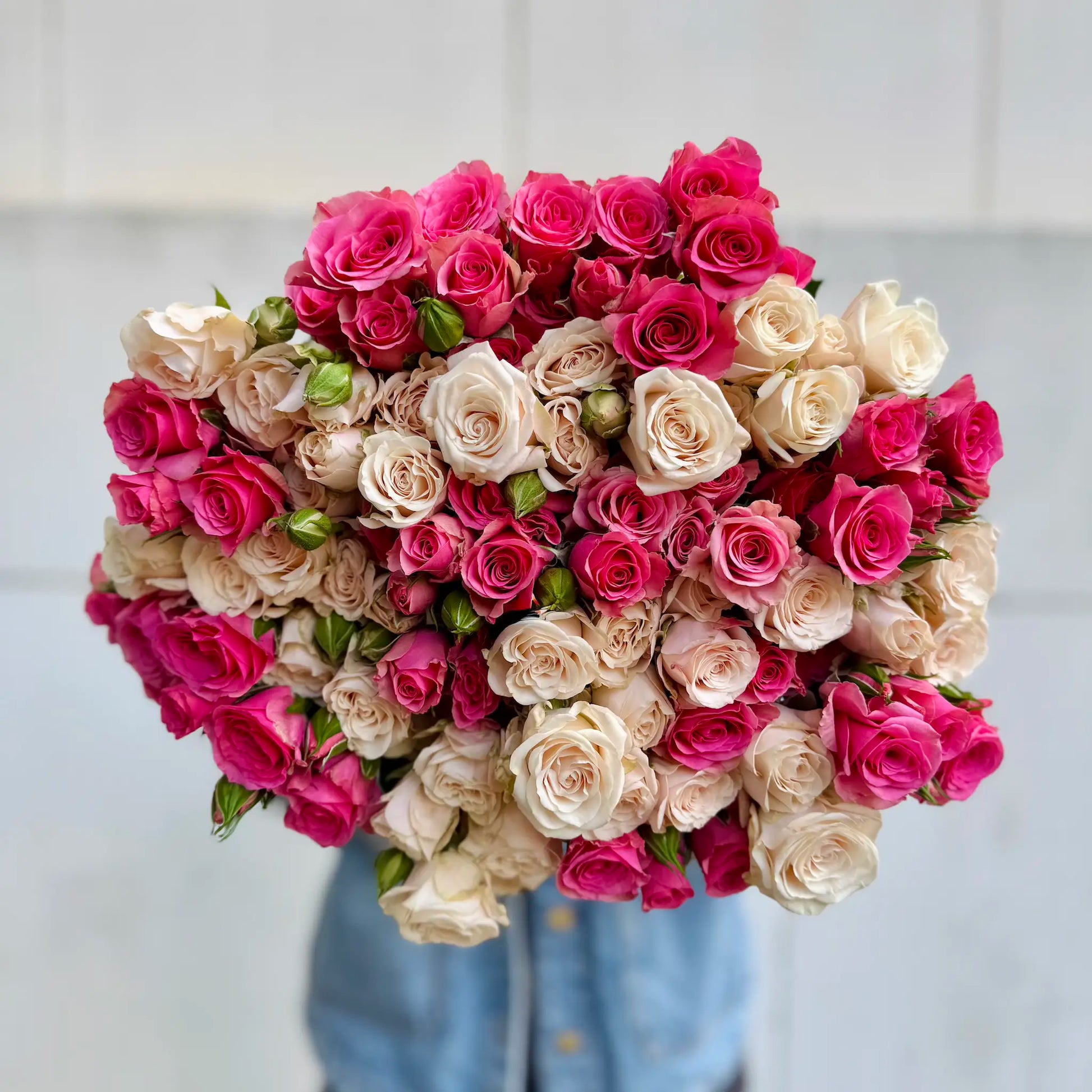 Heart-shaped bouquet of pink and white spray roses on a light background