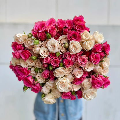 Heart-shaped bouquet of pink and white spray roses on a light background