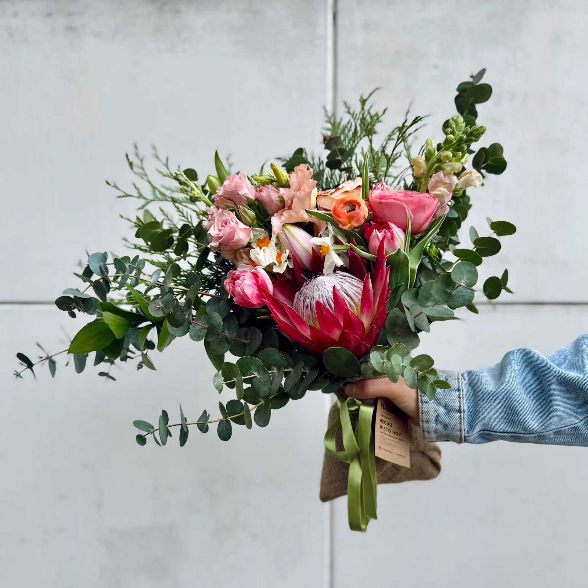 Bouquet of flowers held by a person against a light gray background